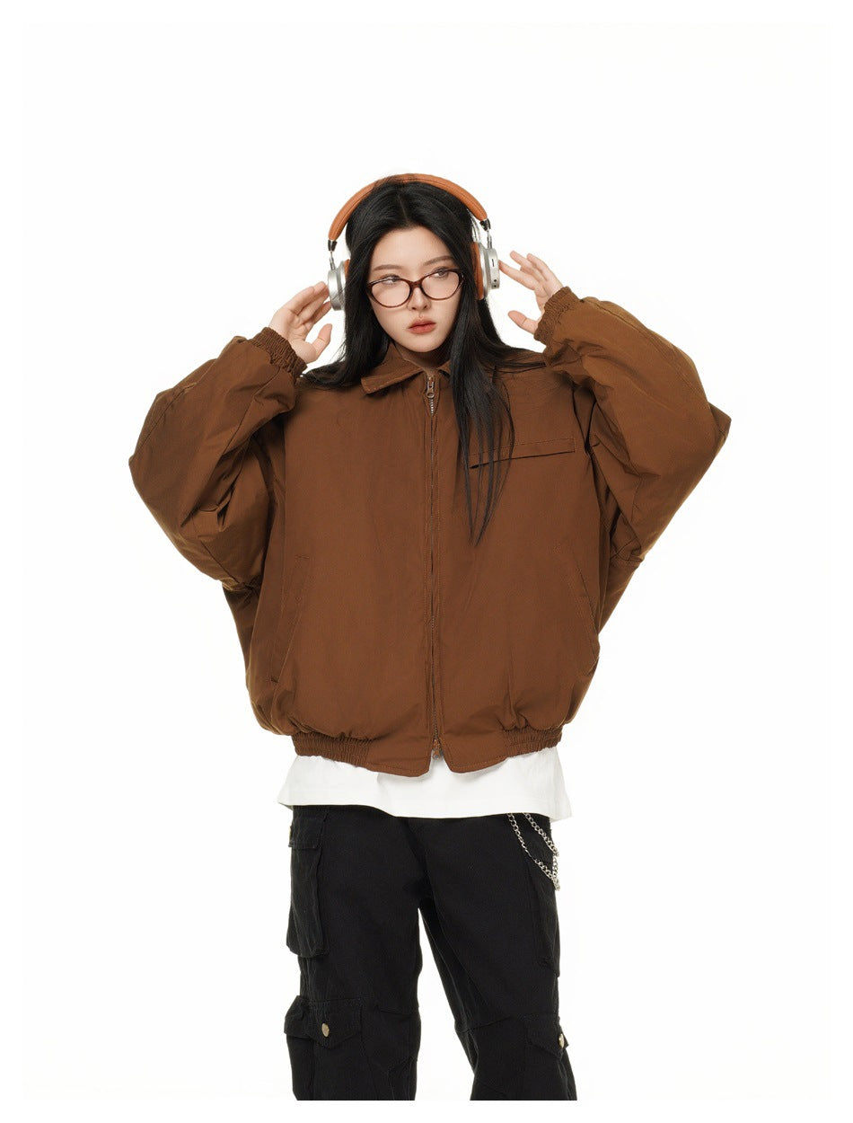 Front view of a model wearing a brown zip-up jacket with a chest pocket, roomy sleeves, and elastic cuffs and hem.