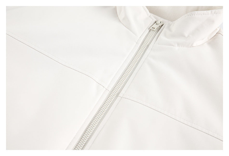 Close-up of an ivory jacket's front zipper, collar, and diagonal seam stitching.