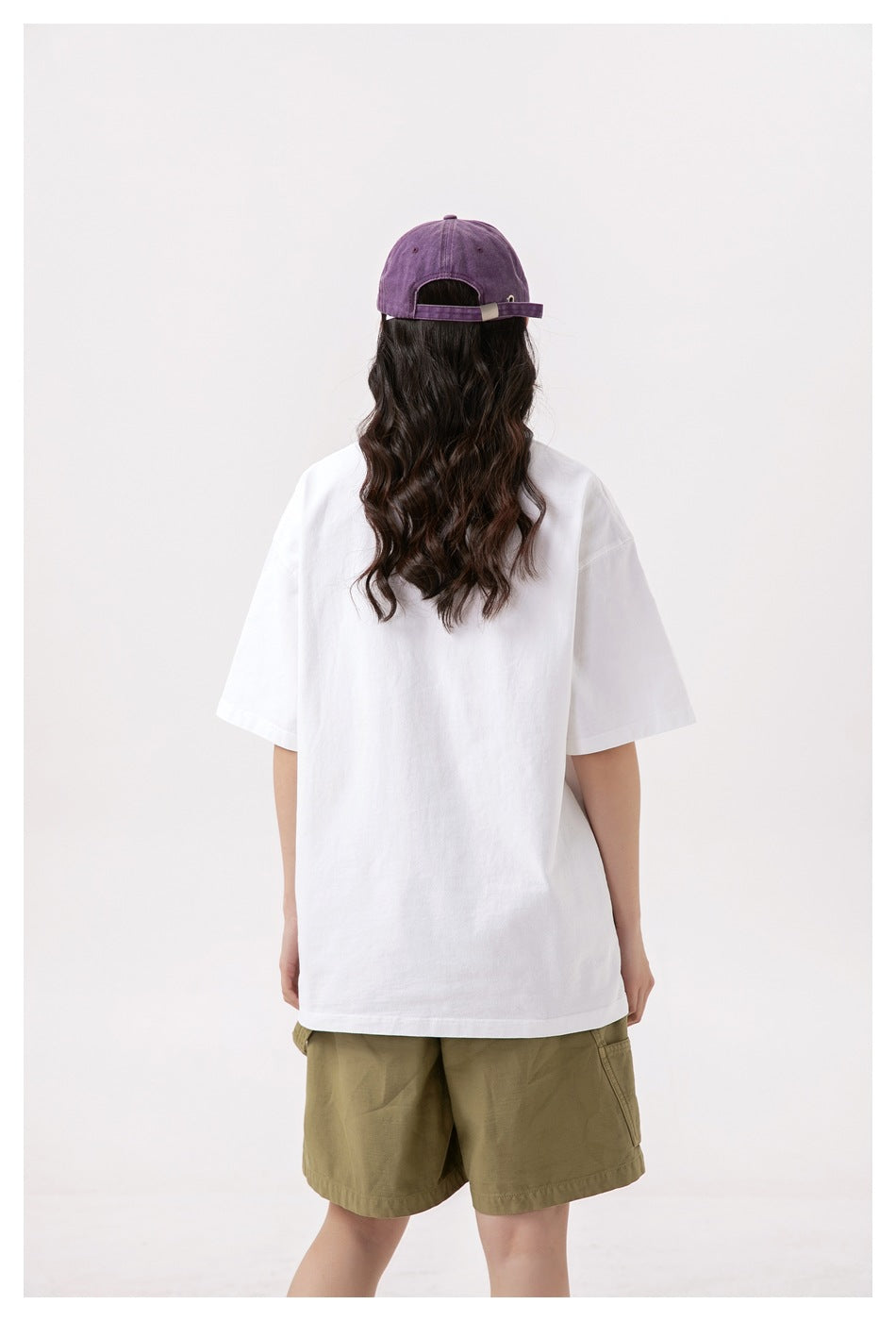 Back view of a model wearing an oversized plain white T-shirt and olive shorts.