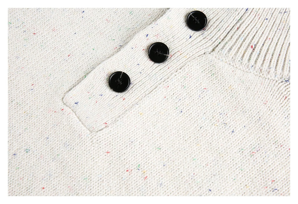 Close-up of a cream flecked knit button placket with three black buttons and ribbed trim.
