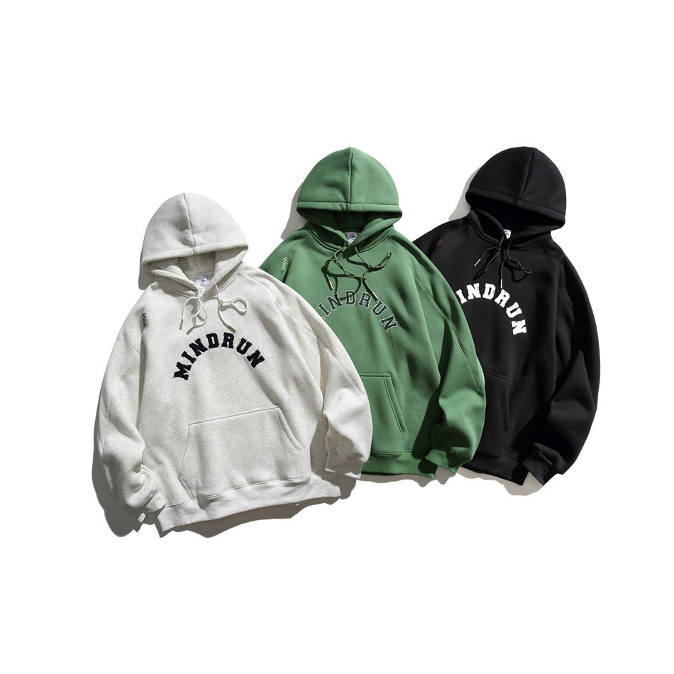 Three hoodies displayed together in light gray, green and black, each with a kangaroo pocket and arched chest lettering.