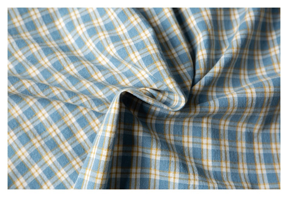Close-up of the blue, white, and mustard plaid fabric gathered to show its pattern and drape.