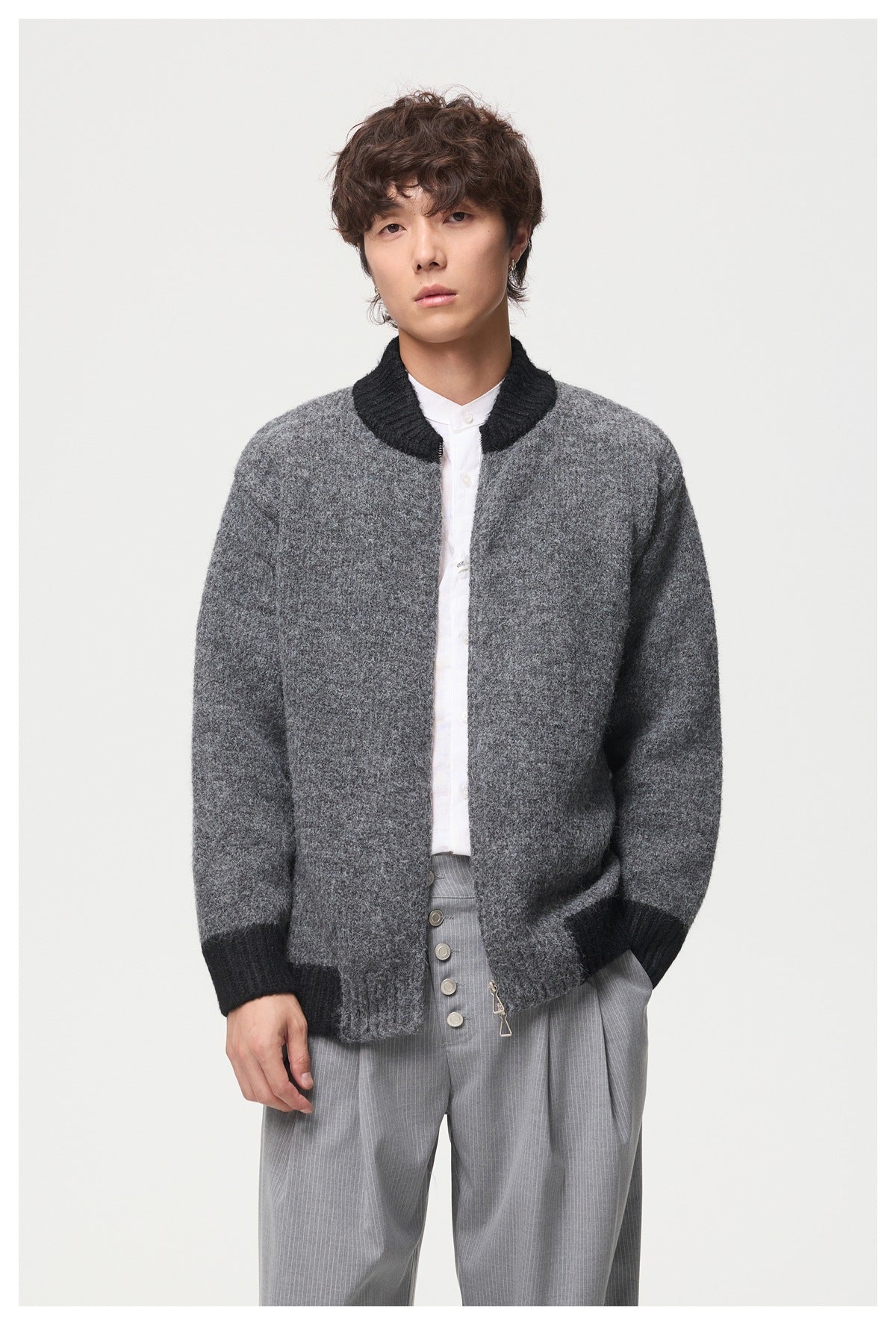 Closer front view of a model wearing a gray cardigan with black ribbed trim and a front zipper.
