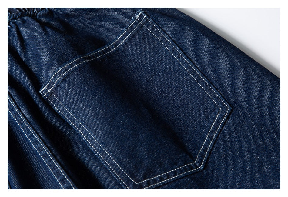 Close-up of a large back pocket on dark indigo denim shorts, outlined with contrasting white stitching.