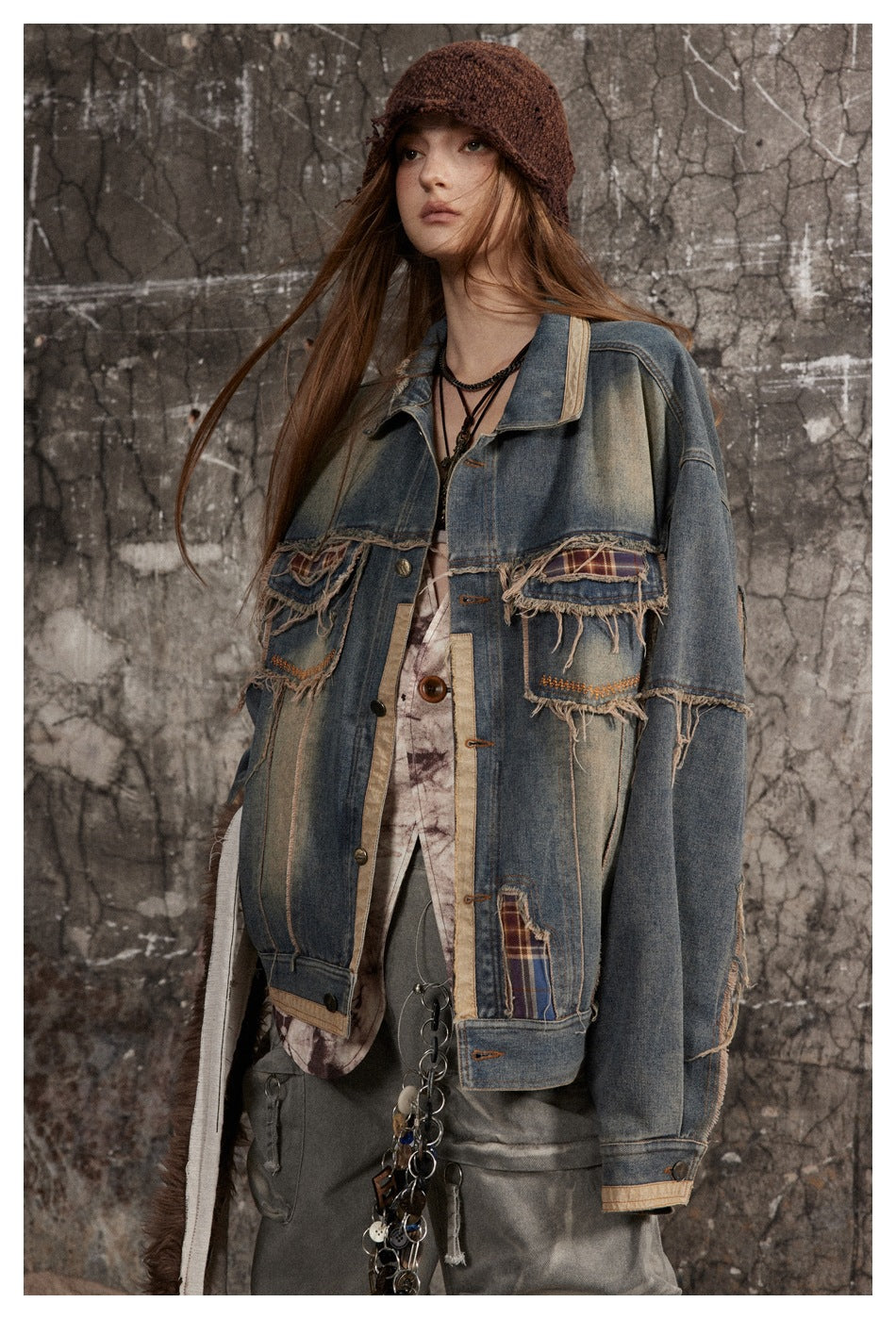 Model wearing an oversized patchwork denim jacket with frayed plaid-trimmed pockets and tan edging.