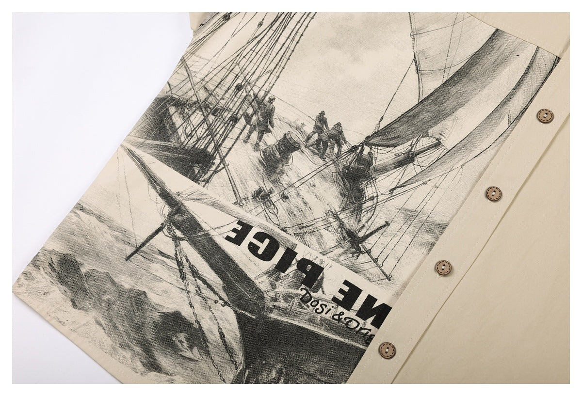 Close-up of a beige shirt with a large black-and-gray sailing ship illustration and printed lettering.