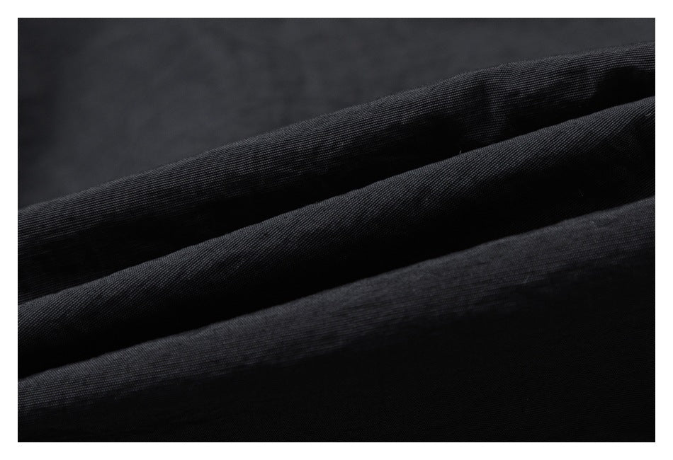Macro view of the black garment fabric, showing its fine woven texture.