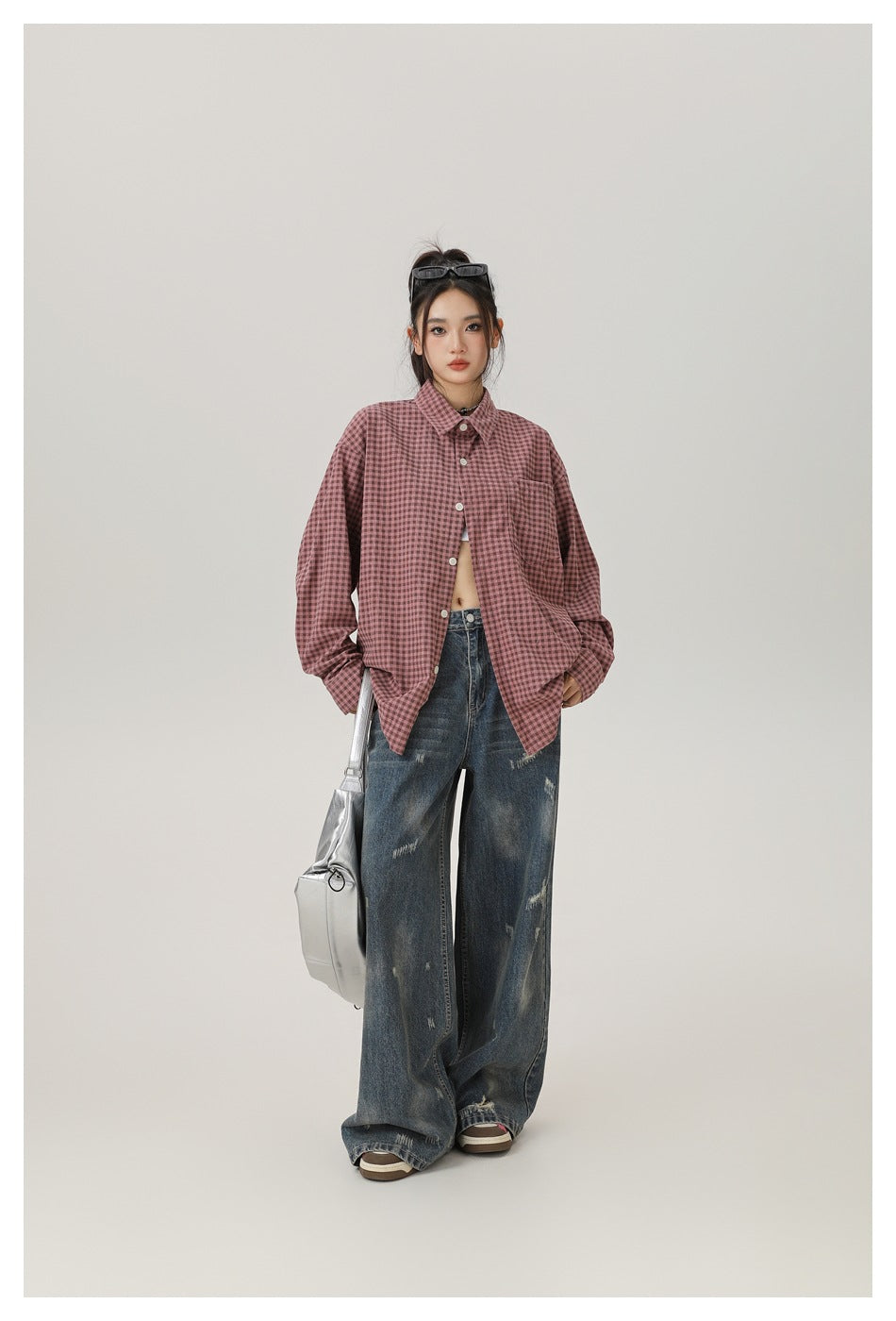Model wearing a dusty rose and dark checked button-up shirt with oversized sleeves and loose distressed jeans, front view.