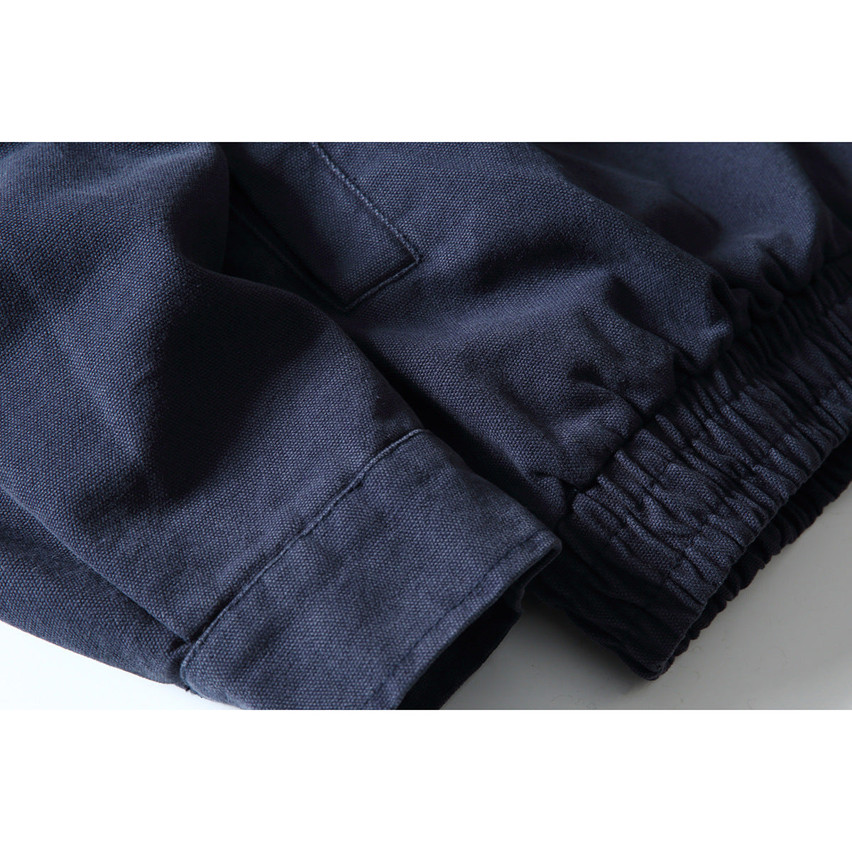 Close-up of a navy jacket's elastic hem and buttoned sleeve cuff.