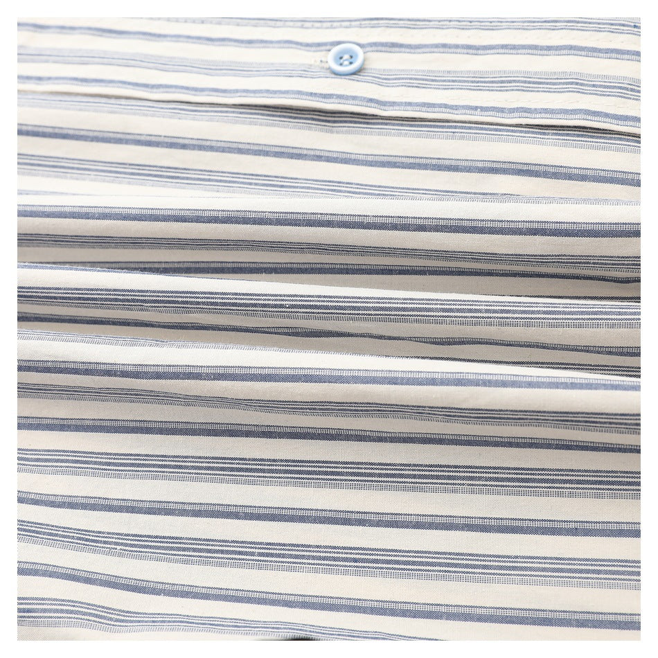 Close-up of a pale blue button on cream fabric with horizontal blue-gray stripes.