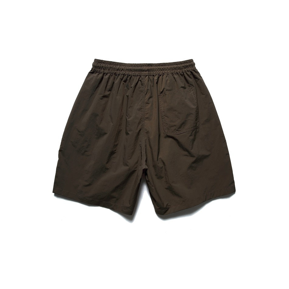 Back view of dark brown shorts with an elastic waistband and a single patch pocket.