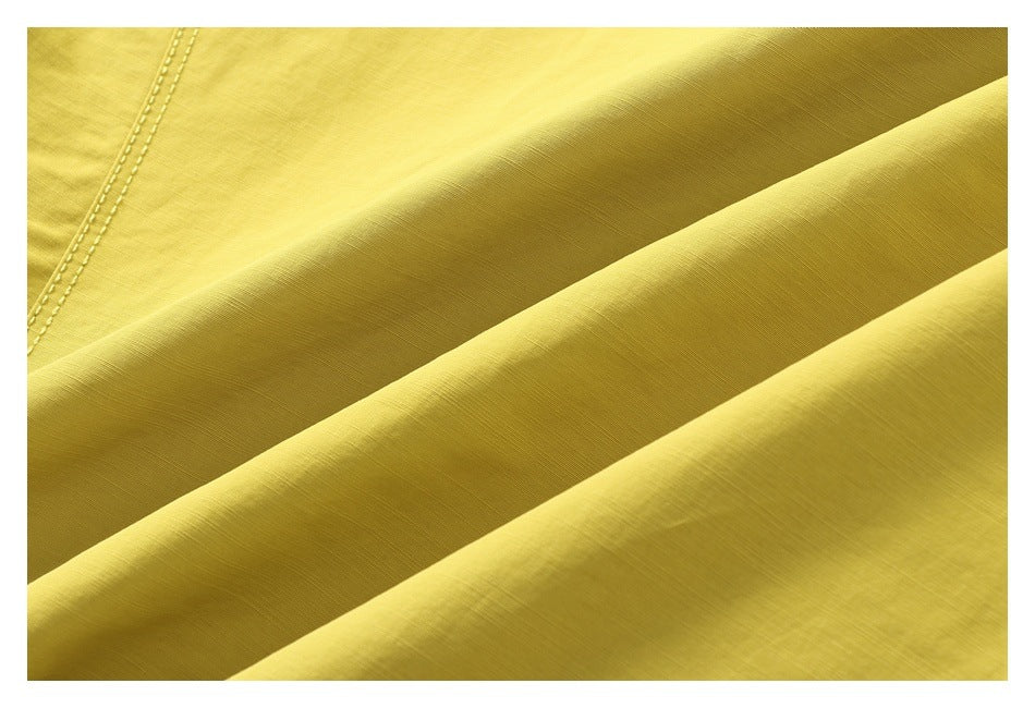Close-up of yellow jacket fabric draped into folds, with a stitched seam visible at the upper left.