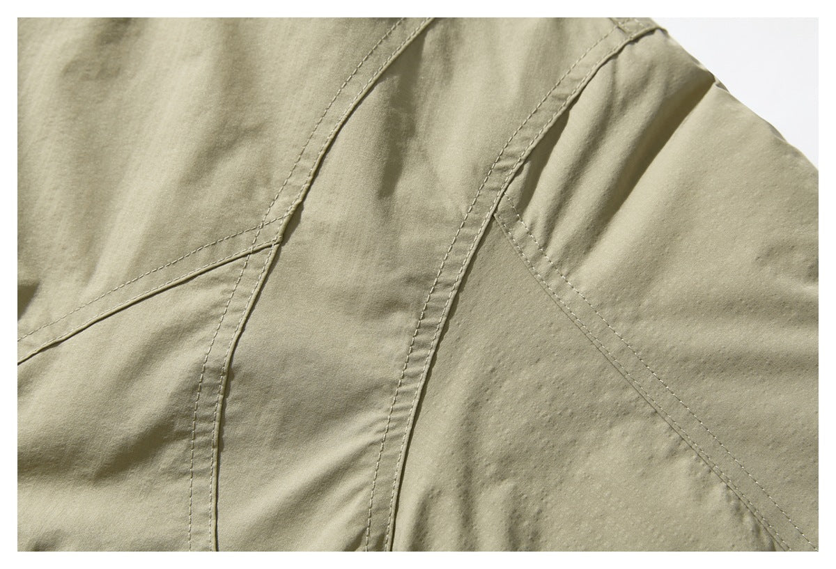 Close-up showing curved stitched panel seams on an olive-khaki jacket.