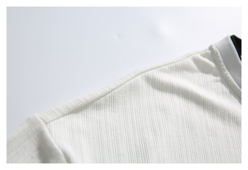 Close-up of the white shirt's ribbed shoulder seam and short-sleeve attachment.