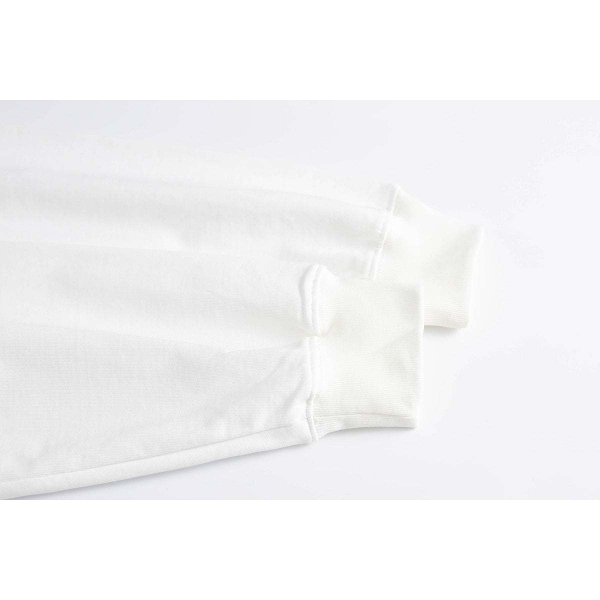 Close-up of the white shirt's long sleeves and ribbed cuffs, showing the fabric and stitching.