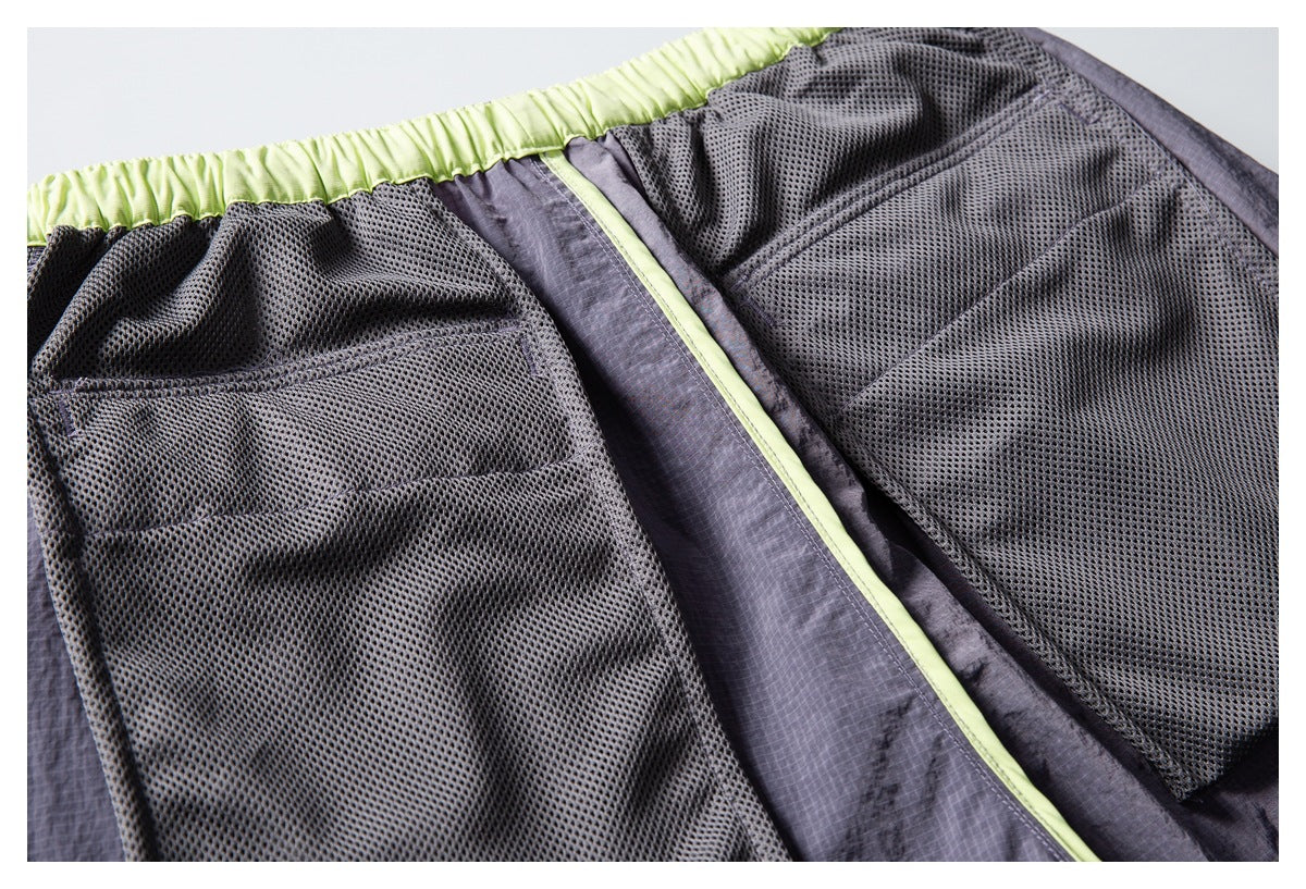 Close-up of gray shorts interior with black mesh lining, lime-green elastic waistband, and a trimmed seam.