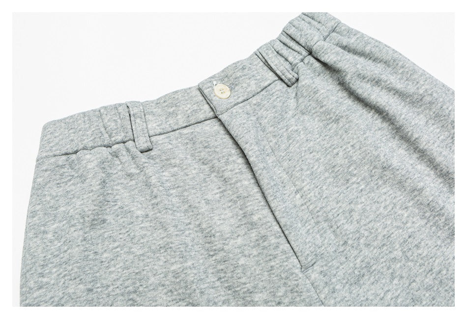 Close-up of heather gray pants showing the waistband, belt loops, button, and front seam.