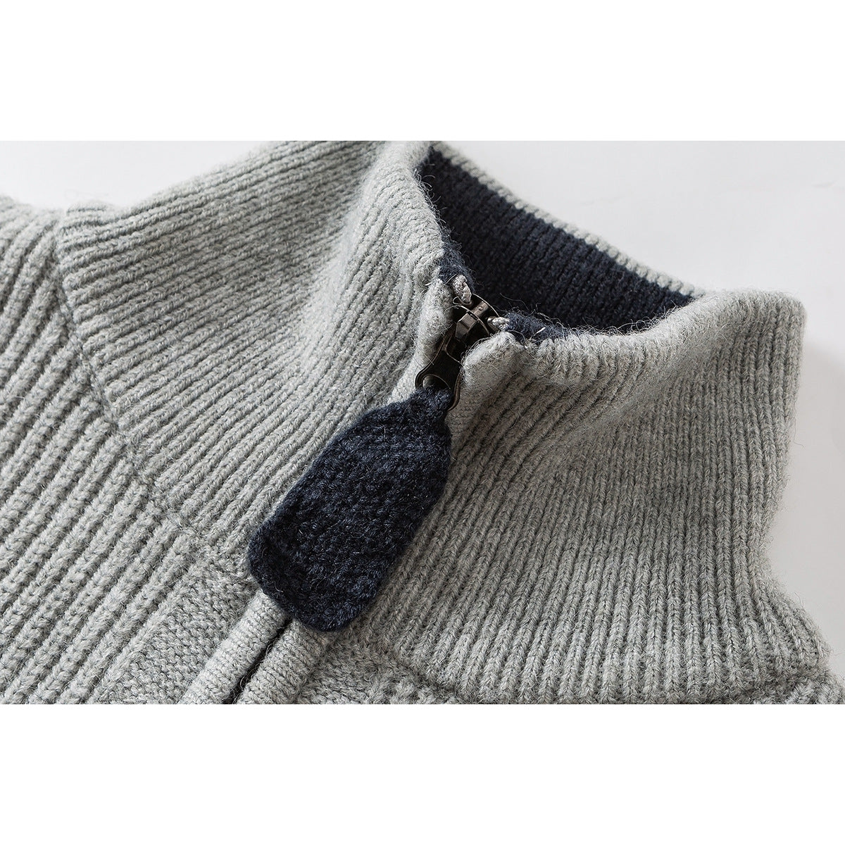Close-up of a gray rib-knit sweater’s high collar and zipper with a dark navy knit zipper pull.