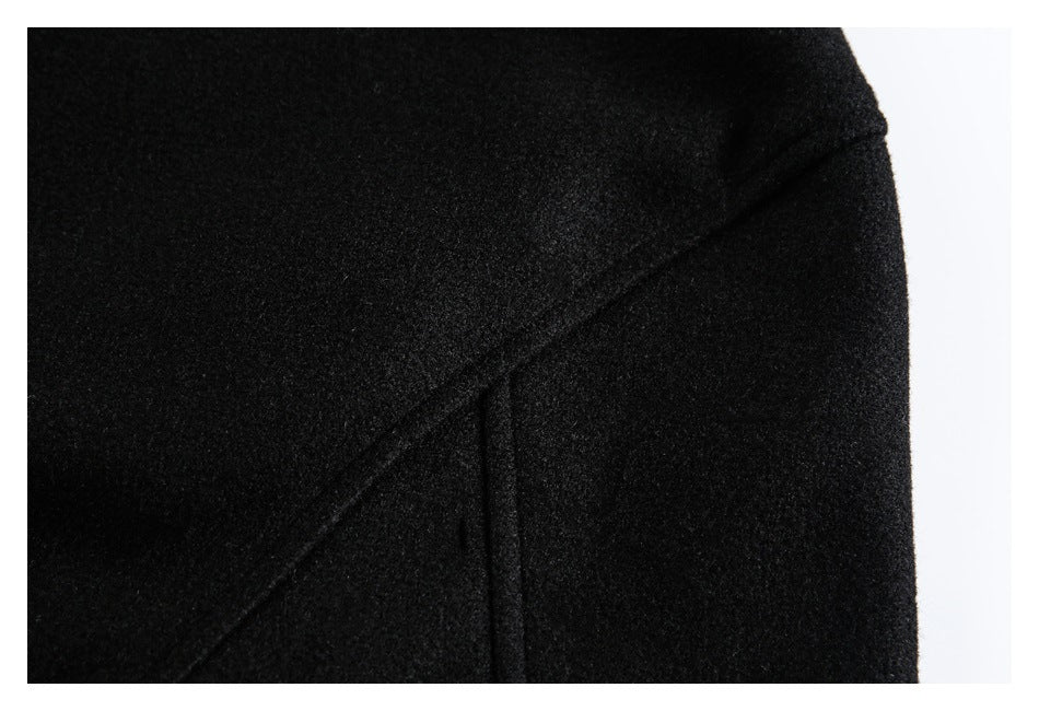 Close-up of black garment fabric showing a curved seam and a vertical stitched line.