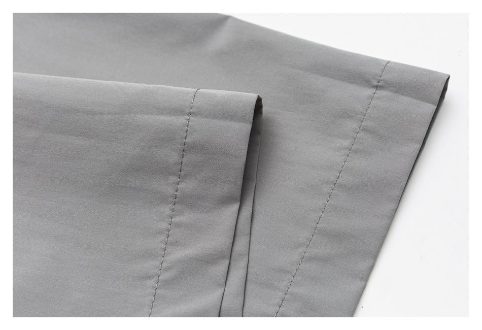 Close-up of gray garment fabric with two stitched seams and a folded edge.