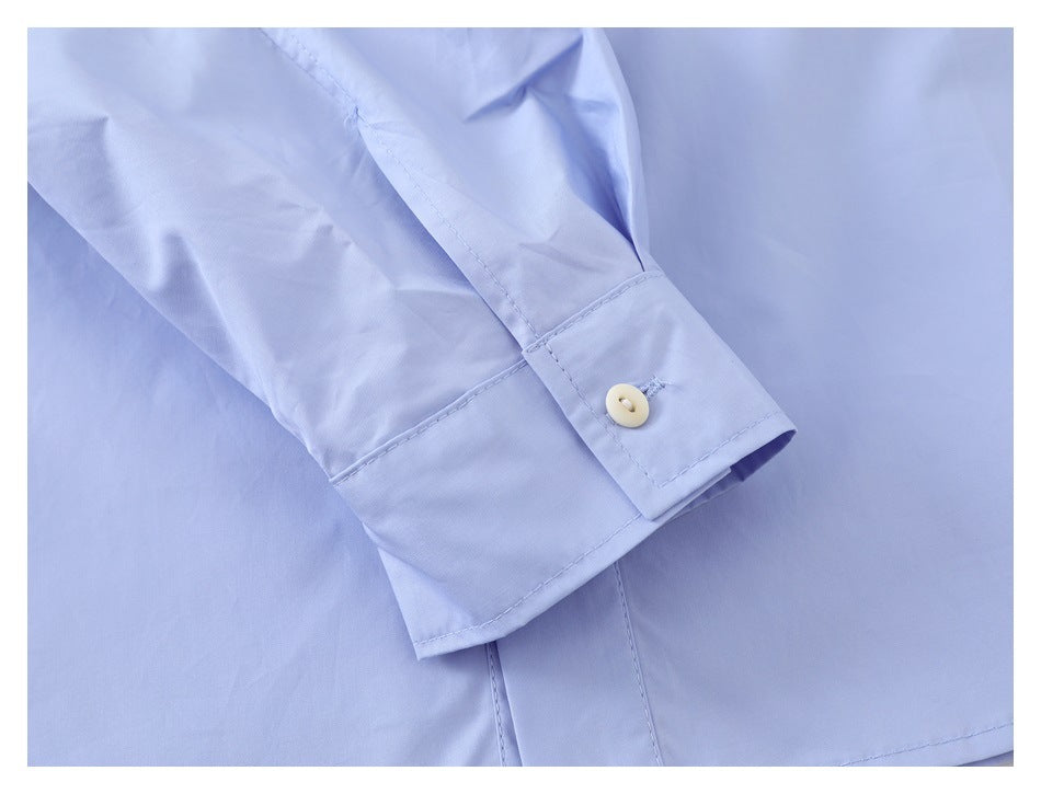 Close-up of a light blue shirt cuff with a cream button and visible stitching.
