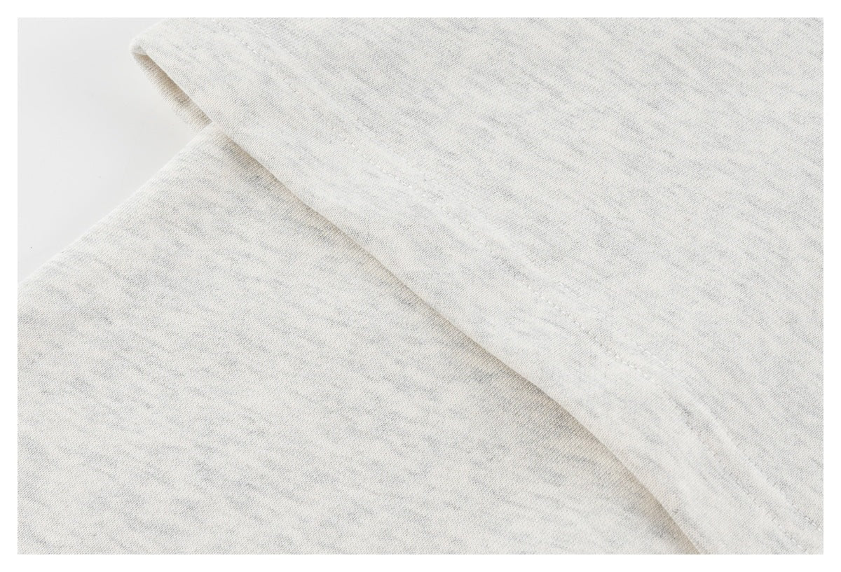 Close-up of a seam on light gray fabric, showing the fine heathered texture.