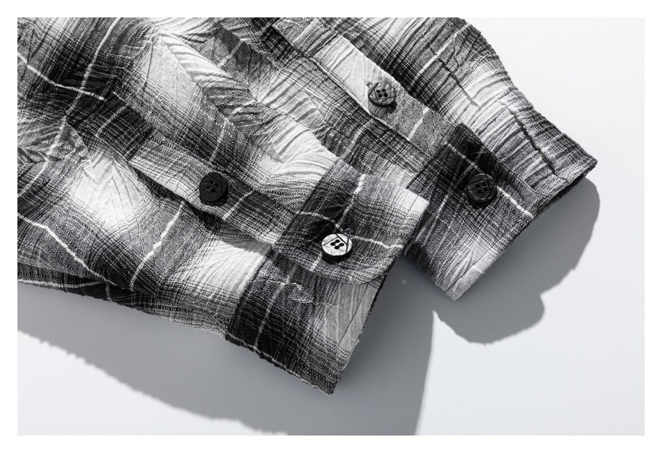 Close-up of black buttons and a cuff on a black-and-white plaid garment.