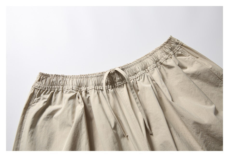Close-up of beige trousers showing the gathered elastic waistband and long matching drawstring.