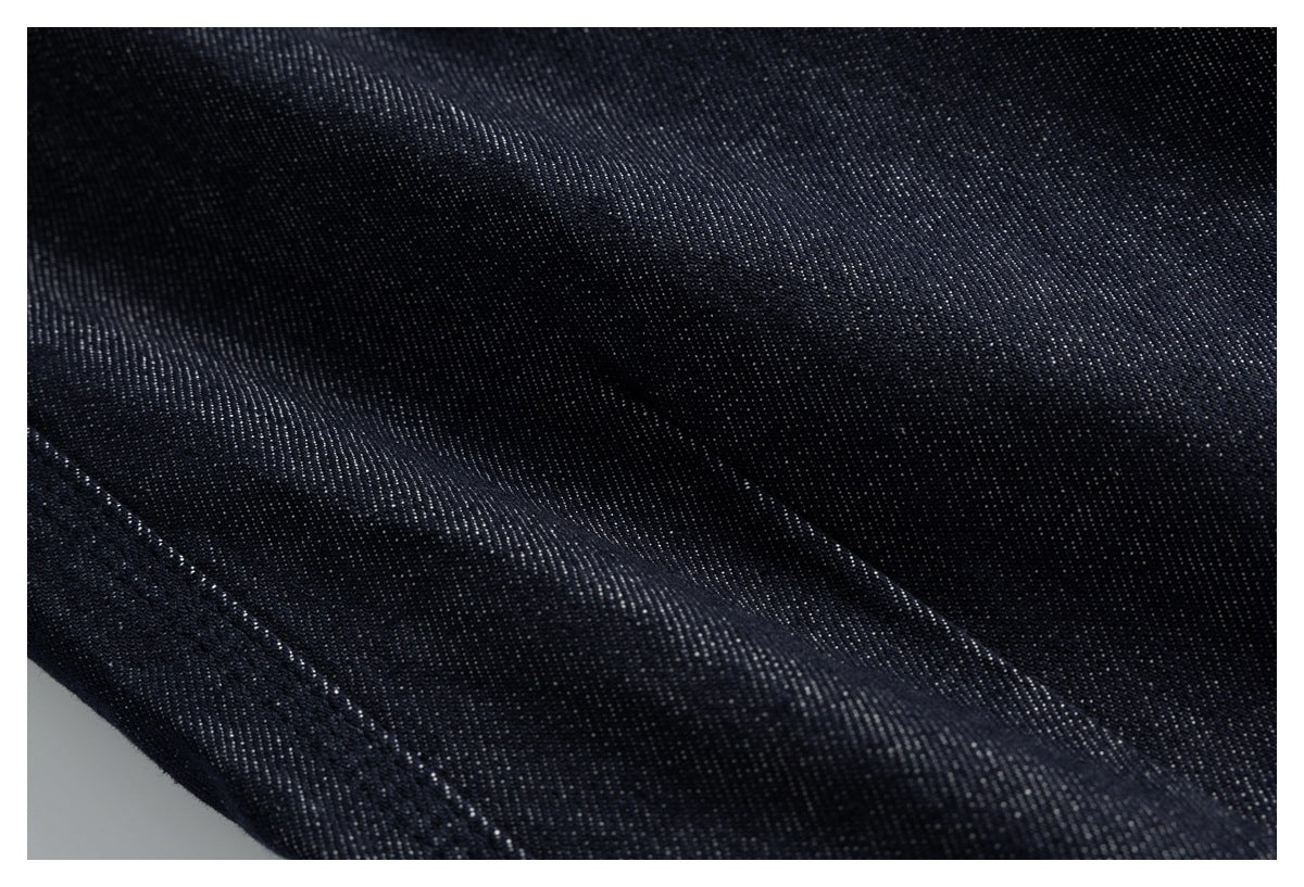Extreme close-up of dark indigo denim twill texture and stitching.