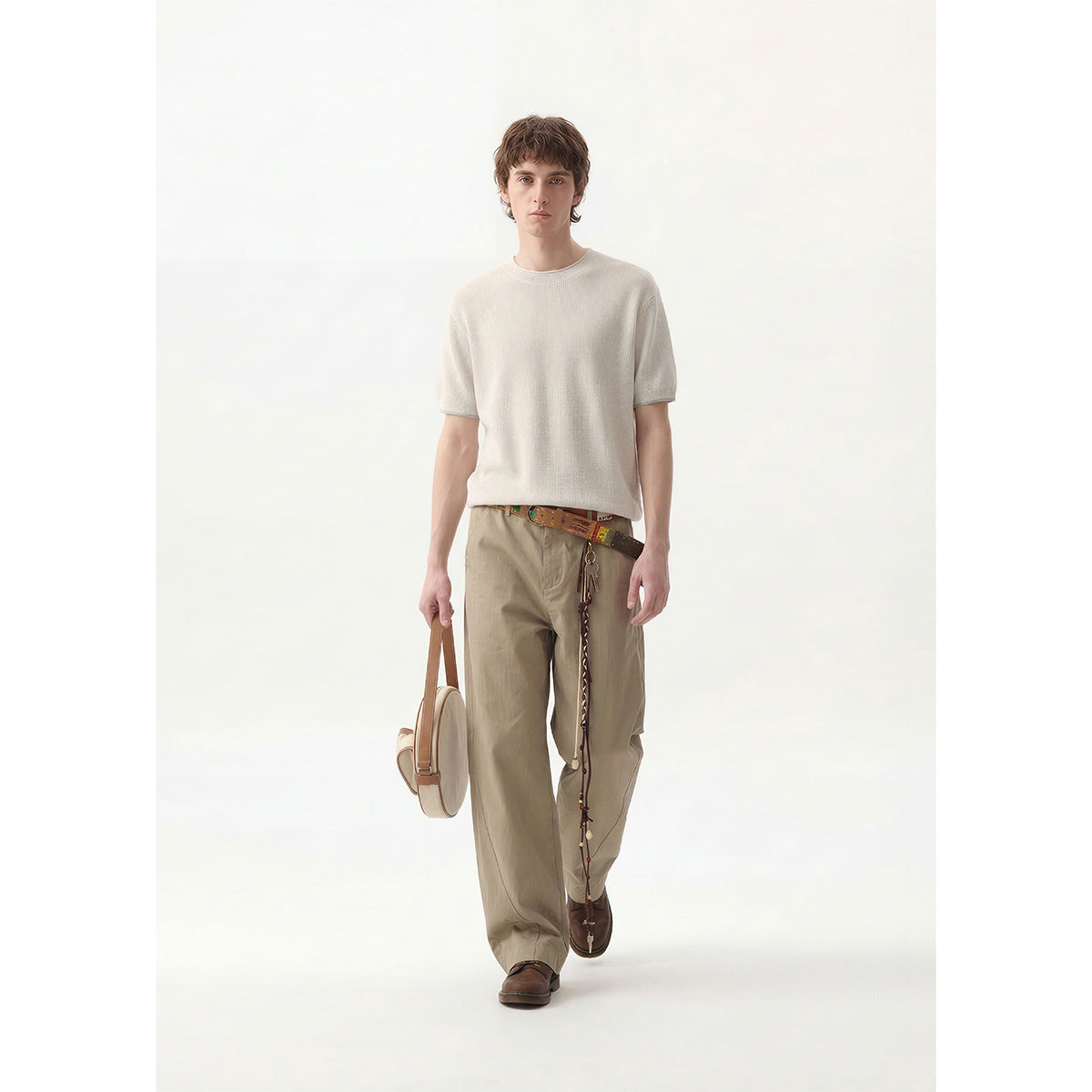 Full-length front view of a model wearing an off-white short-sleeve crewneck top and loose khaki trousers.