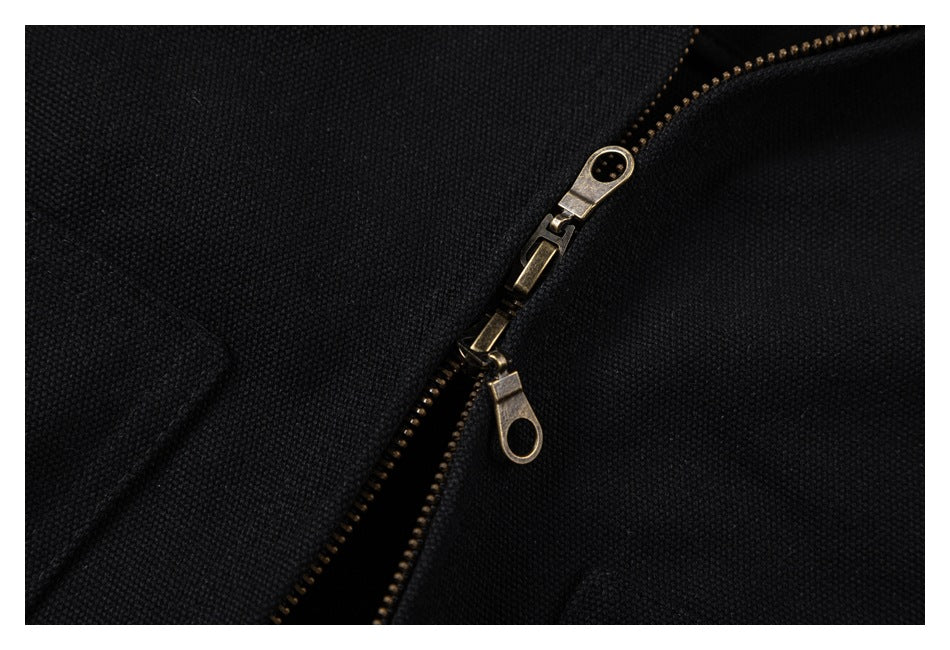 Close-up of a black garment's diagonal brass-tone zipper with two zipper pulls.