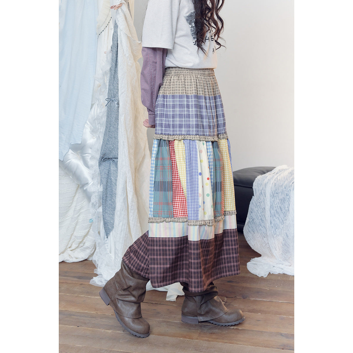 Side view of a model wearing a long patchwork skirt with a dark plaid hem and colorful checked panels.