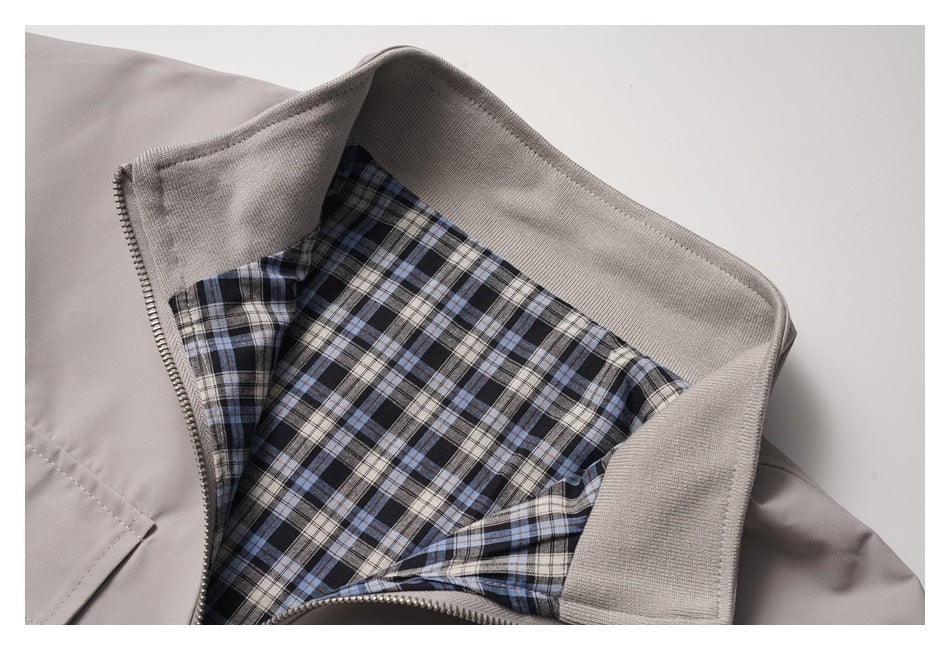 Close-up of a light taupe jacket's zip-front collar, showing a blue, black, and beige plaid lining.