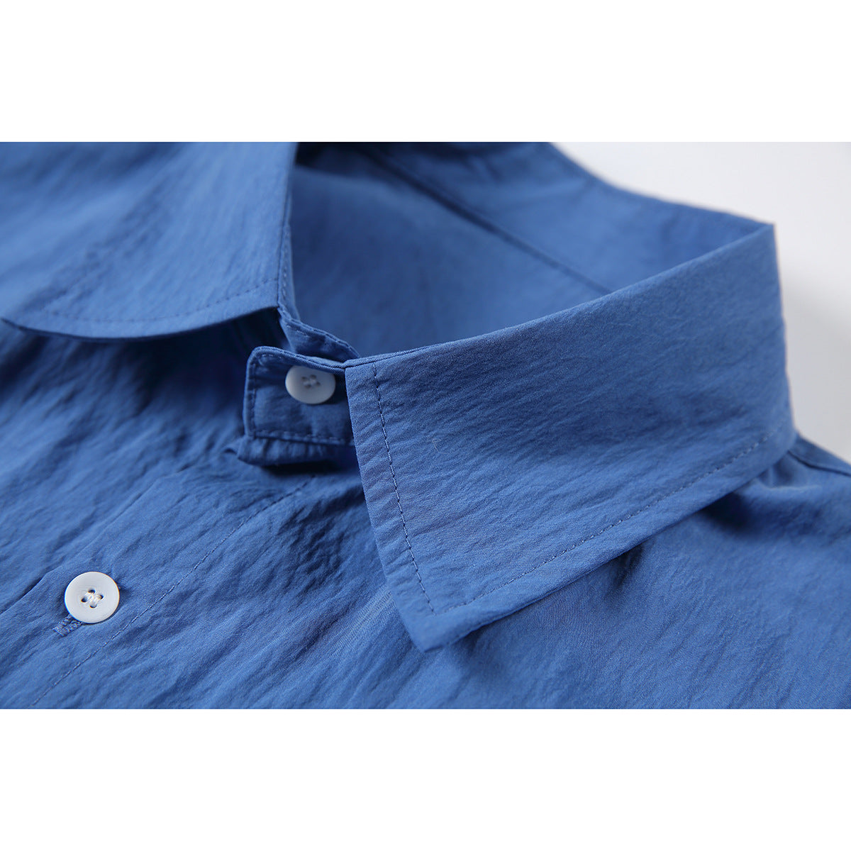 Close-up of a blue button-up shirt collar and white buttons.