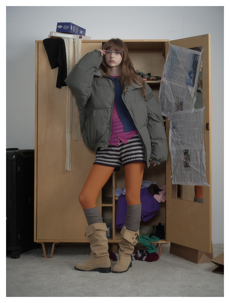 Model wearing an open charcoal-gray puffer jacket with a broad collar, snap closures, and oversized sleeves.