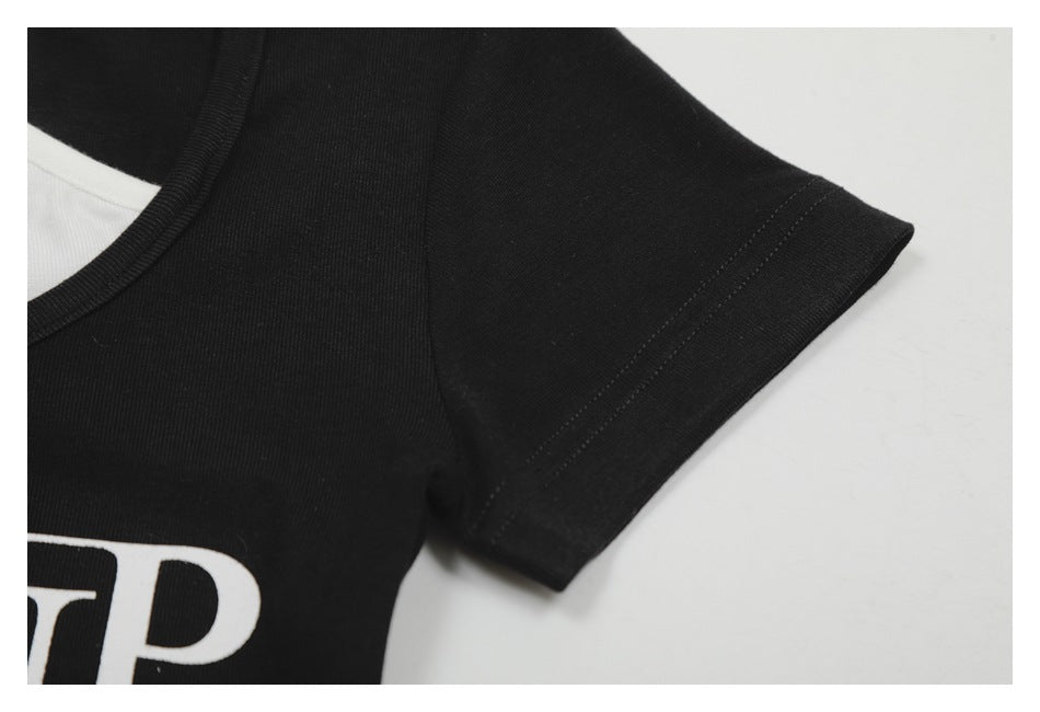 Close-up of a black T-shirt’s crew neck and short sleeve, with part of a white printed design visible.