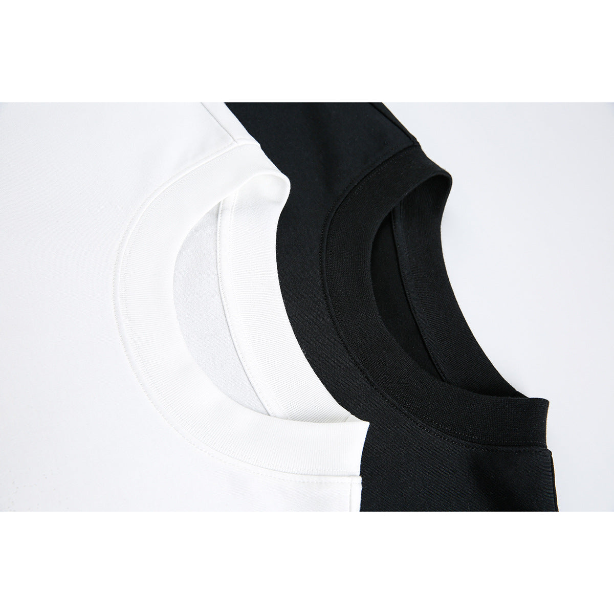 Close-up of overlapping white and black T-shirt crew necks with ribbed collars.