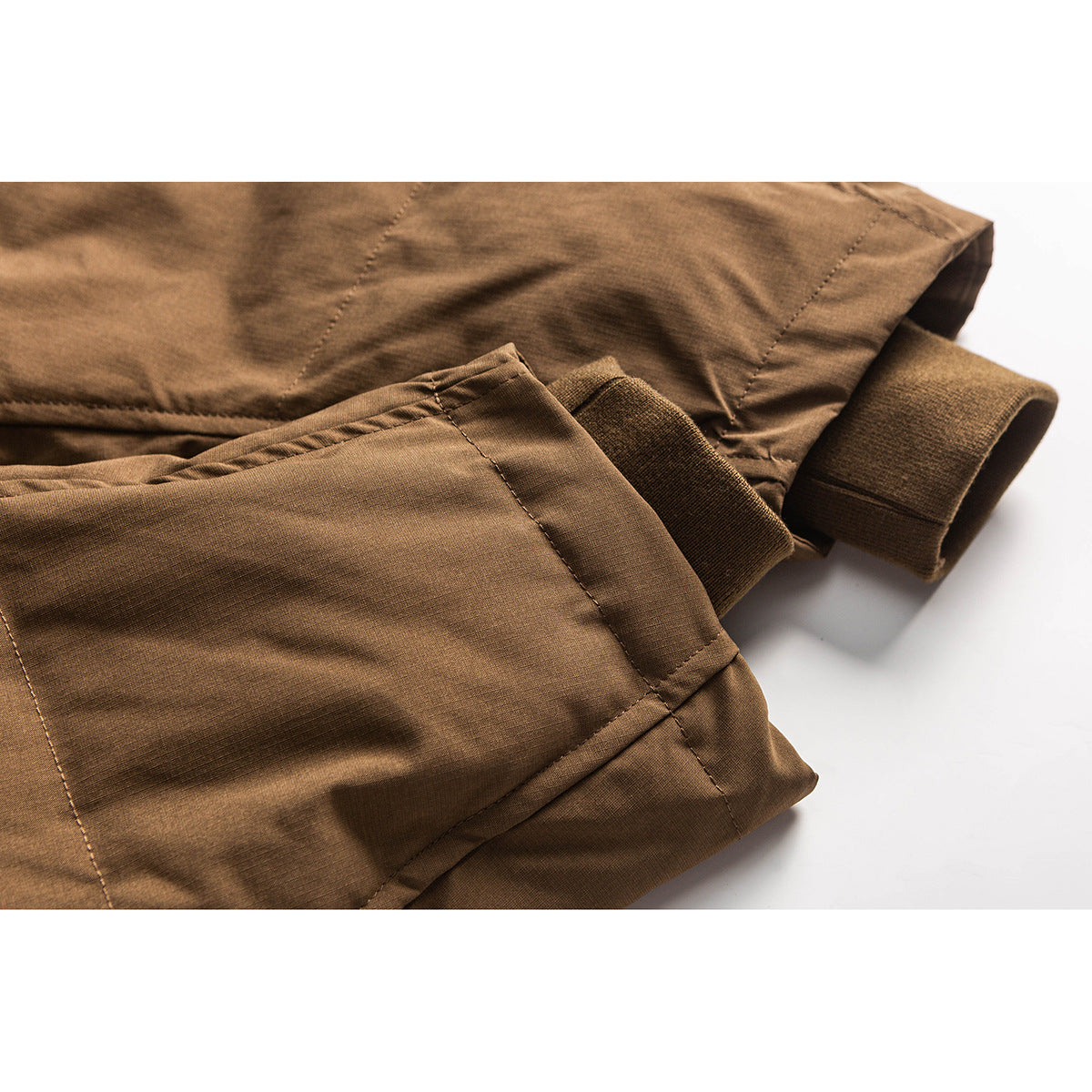 Close-up of a brown jacket sleeve and rib-knit cuff, with seams and fabric texture visible.