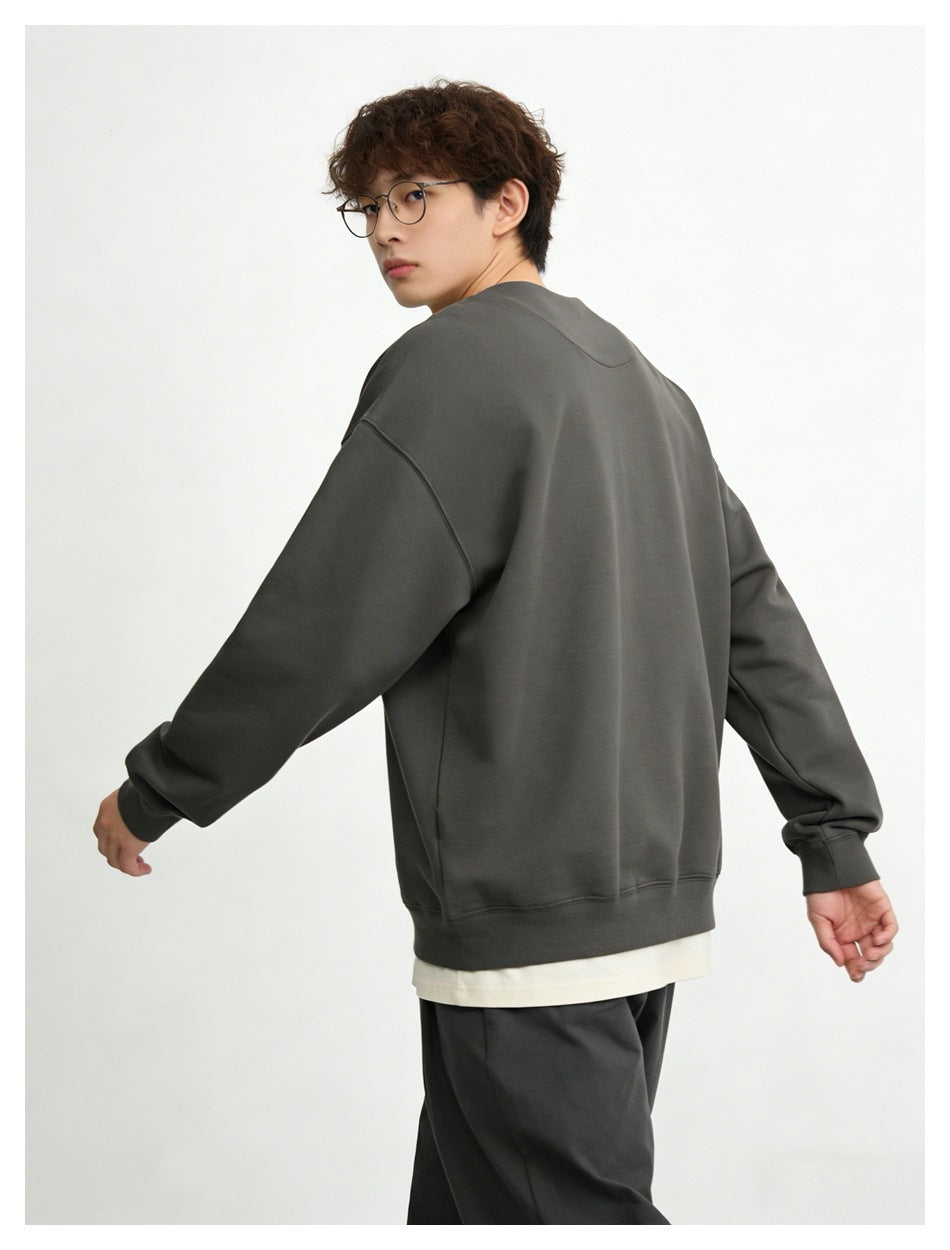 Model turned away in a charcoal sweatshirt with ribbed cuffs and hem, showing the back.