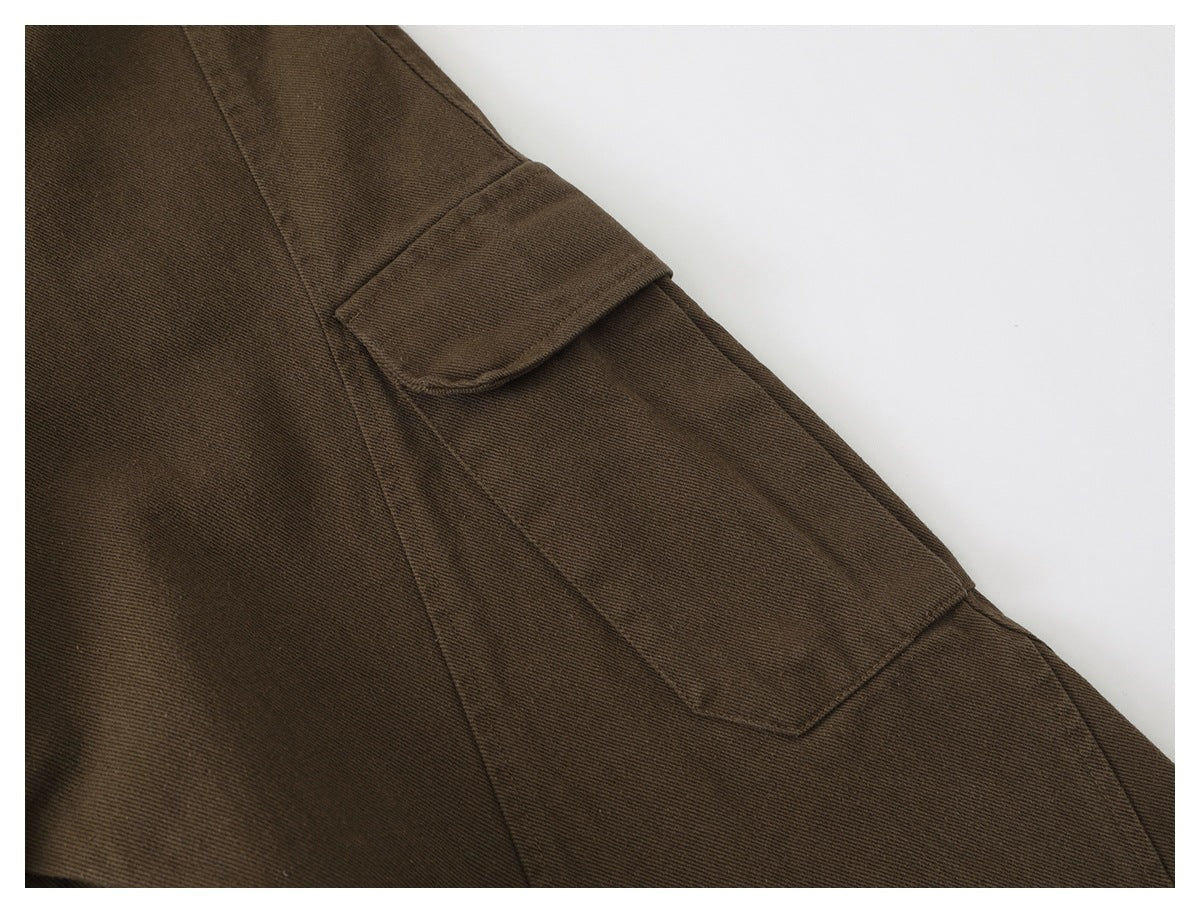 Close-up of a flap pocket and panel seams on brown trousers.