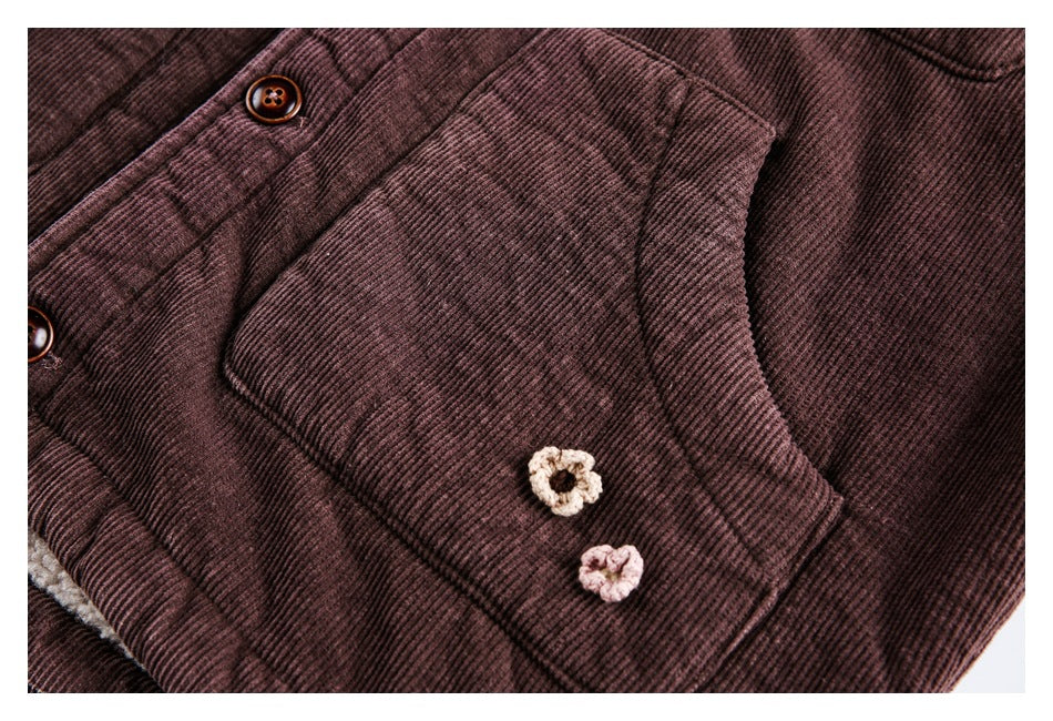 Close-up of a plum-brown ribbed jacket pocket with cream and pink crochet flowers and part of the button placket.