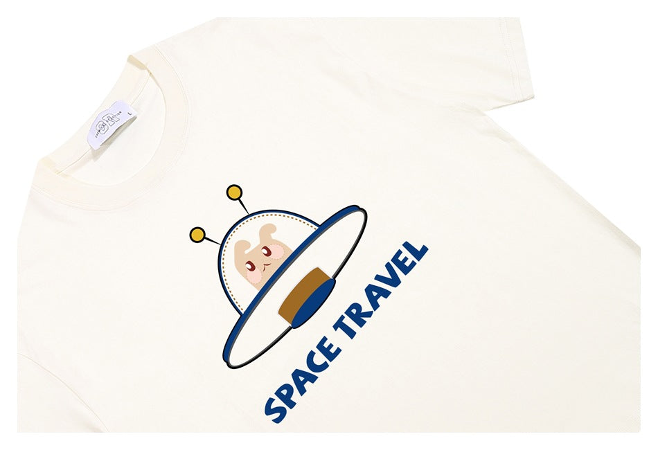 Ivory short-sleeve T-shirt laid flat, printed with a cartoon flying saucer and the words “SPACE TRAVEL.”
