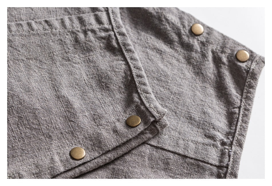 Close-up of gray garment construction with a seam and four brass-tone snap buttons.