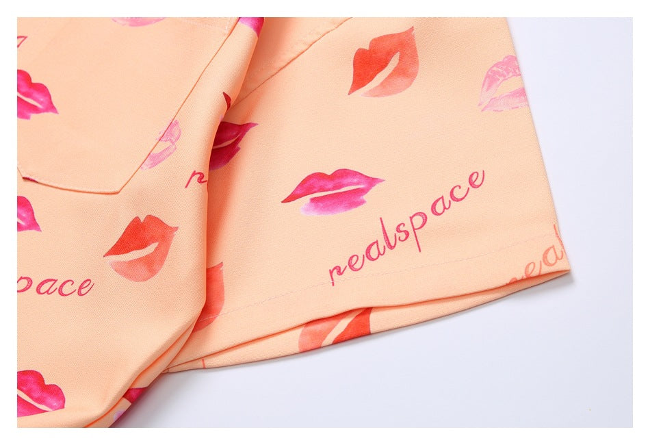 Close-up of peach fabric with pink lip prints and lettering beside a stitched hem.