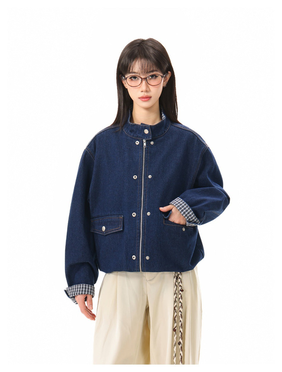 Model wearing a dark blue denim jacket with snap-flap pockets, checked cuffs, and a front zipper.