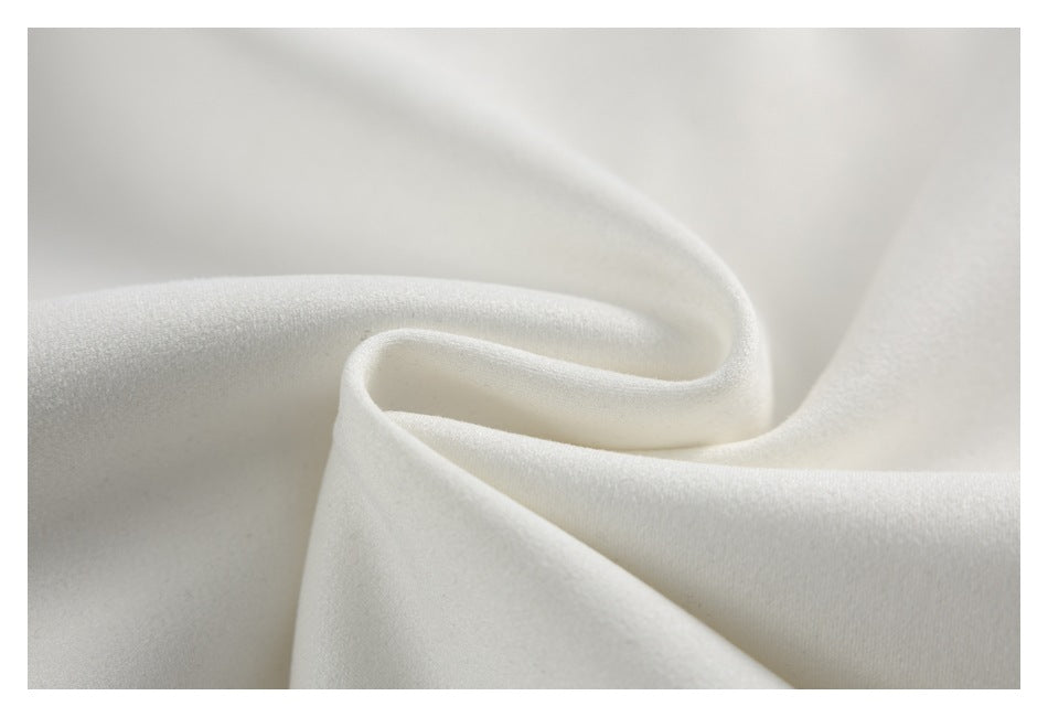 Close-up of softly draped ivory fabric showing its smooth surface and folds.