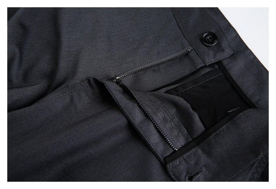 Close-up of charcoal trousers with the buttoned waistband and zipper fly open.