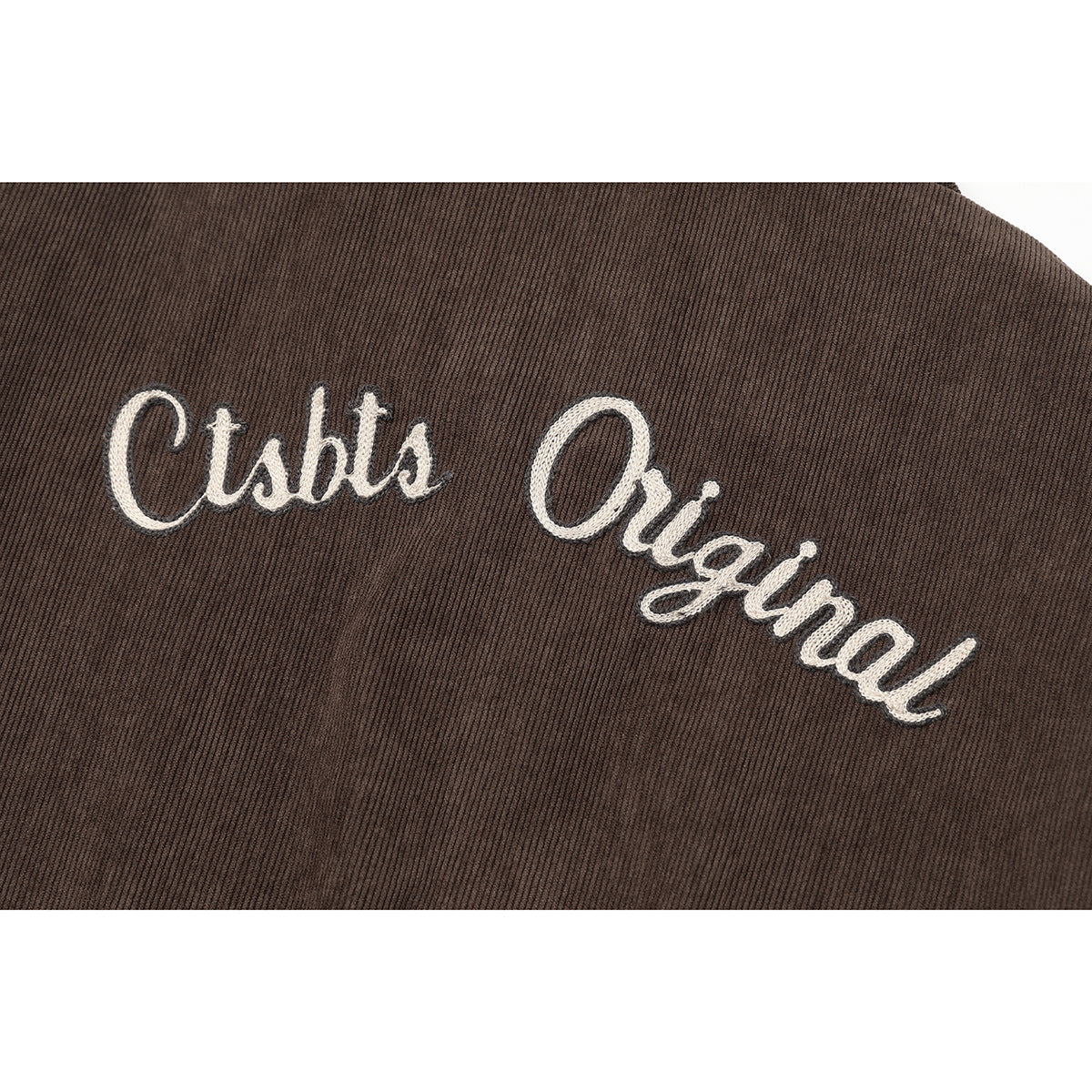Close-up of large white script embroidery on the brown jacket back.