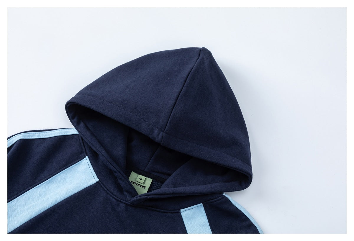 Close-up of a navy hoodie hood and shoulder with light blue panels and a small sewn neck label.