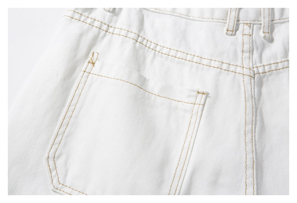 Close-up of one rear patch pocket and tan stitching on white trousers.